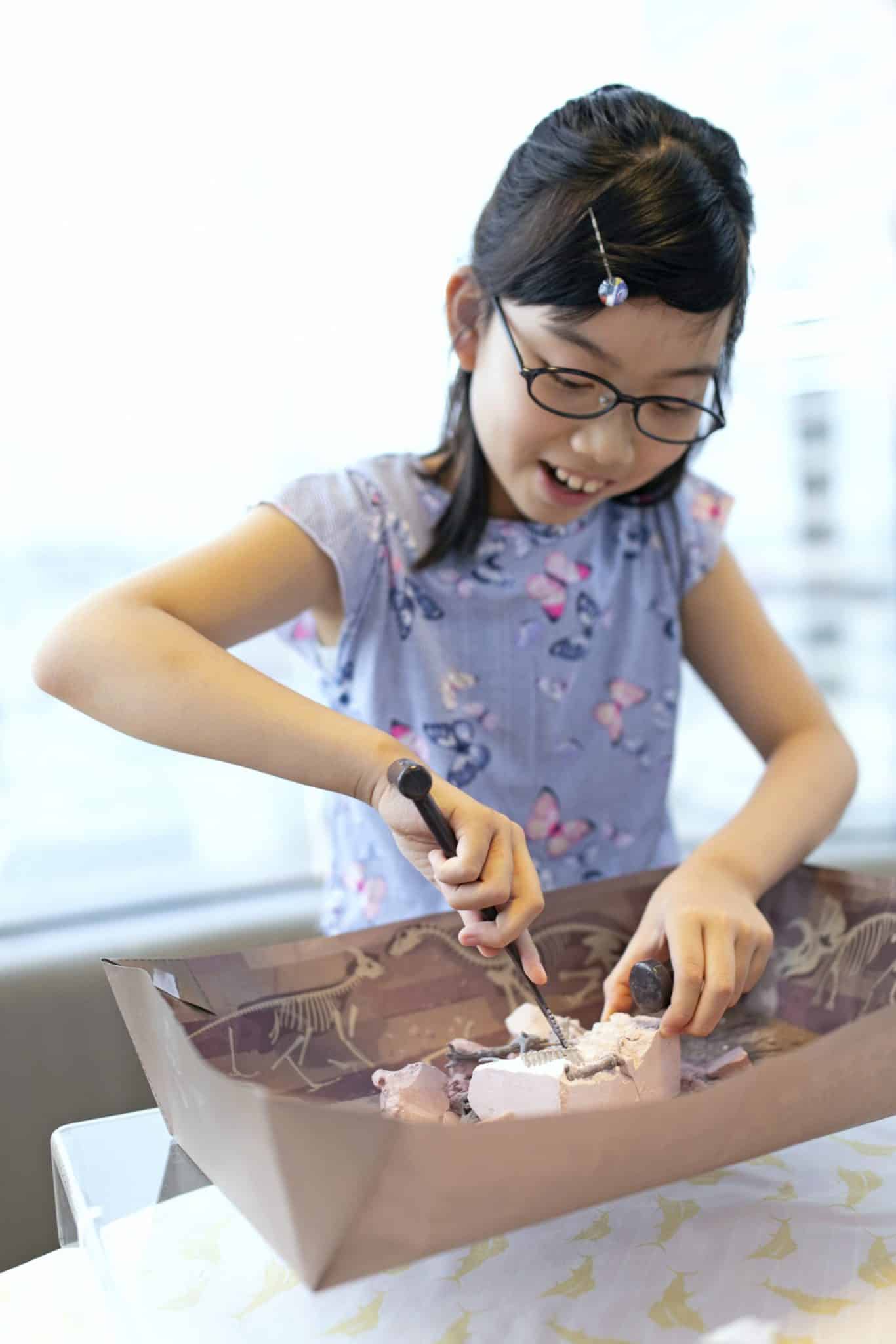 ערכת פלאונטולוגיה לילדים, חפירת שלד דינוזאור Stegosaurus - 4m - ילדה חופרת לגלות שלד דינוזאור